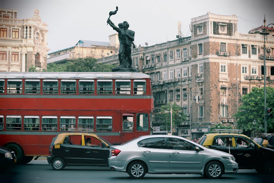 Urban scene featuring a classic red double-decker bus and historic architecture, typical of Mumbai's vibrant streets.