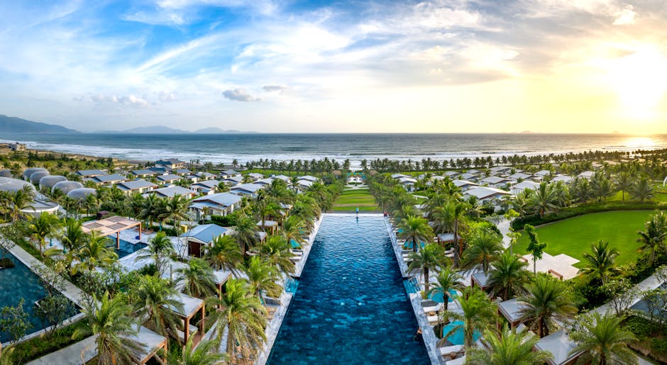Discover a stunning beach resort with lush gardens and infinity pool overlooking the ocean at sunset.