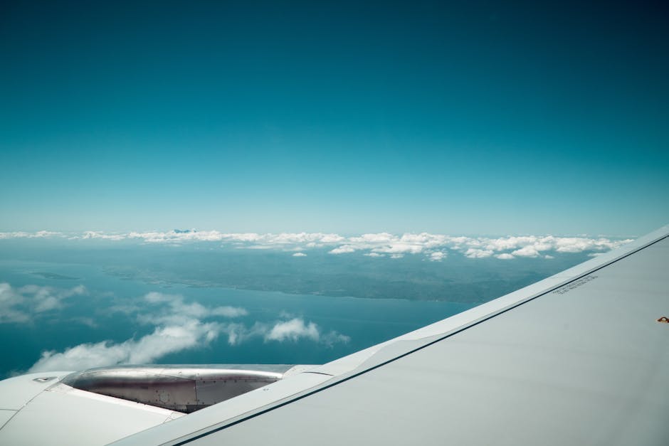 A stunning view from an airplane wing capturing the vast ocean and scattered clouds below.