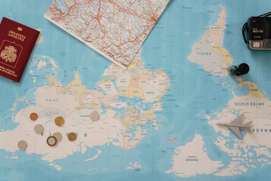 Flat lay of a world map, passport, coins, and camera for travel planning.