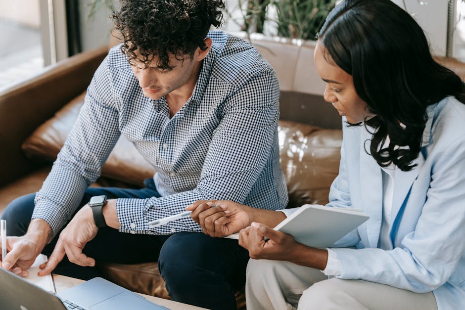 Two coworkers engaged in a collaborative discussion in a modern office setting.