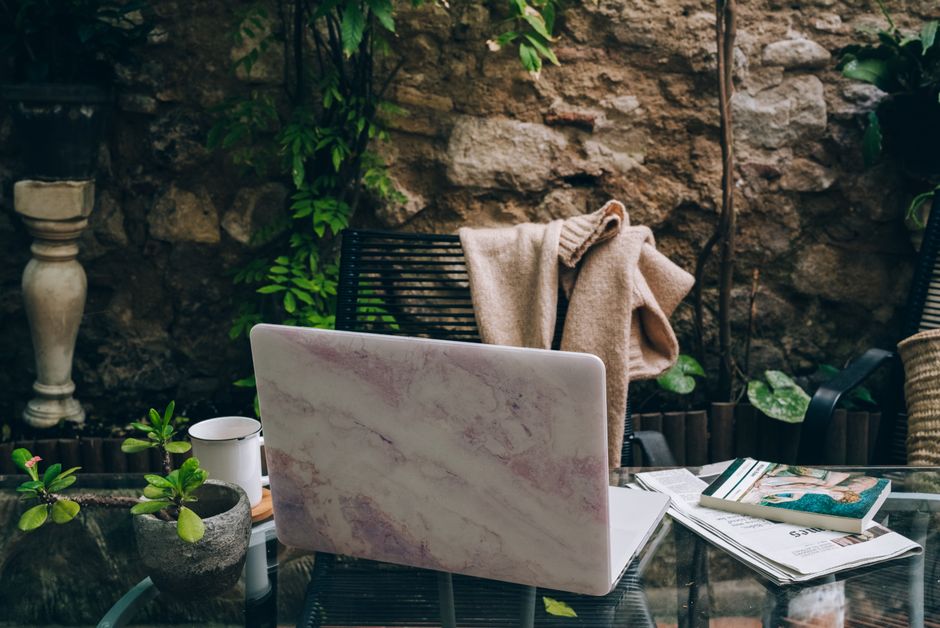 A serene outdoor workspace setup with a marble laptop, coffee cup, and plants for a productive environment.