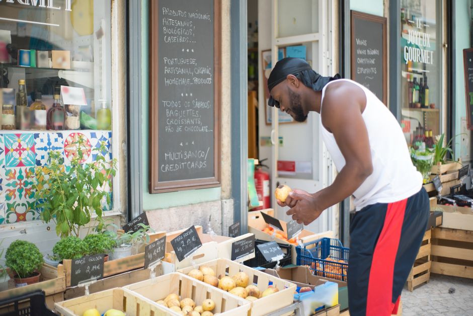 A man selects fresh apples from an outdoor market stand in Portugal.