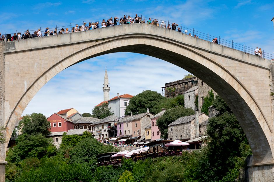 Majestic view of Stari Most bridge arch over Neretva River in Mostar, bustling with tourists.