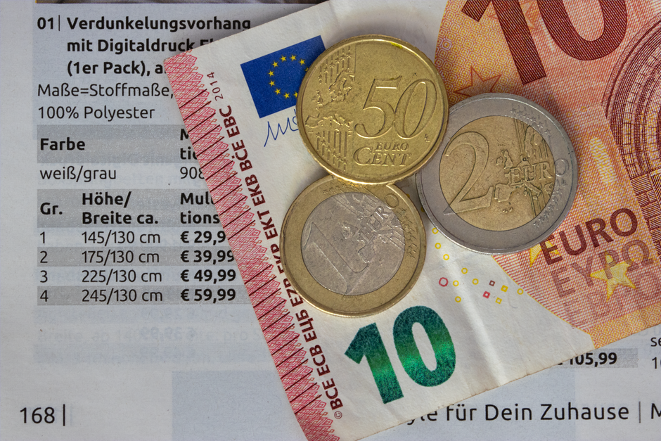 Euro coins and bills on a price list, symbolizing finance and economy.