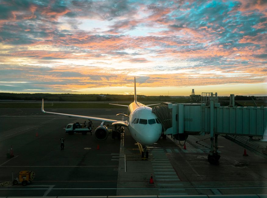 A plane at Makung Airport during a stunning sunset, reflecting vibrant skies.