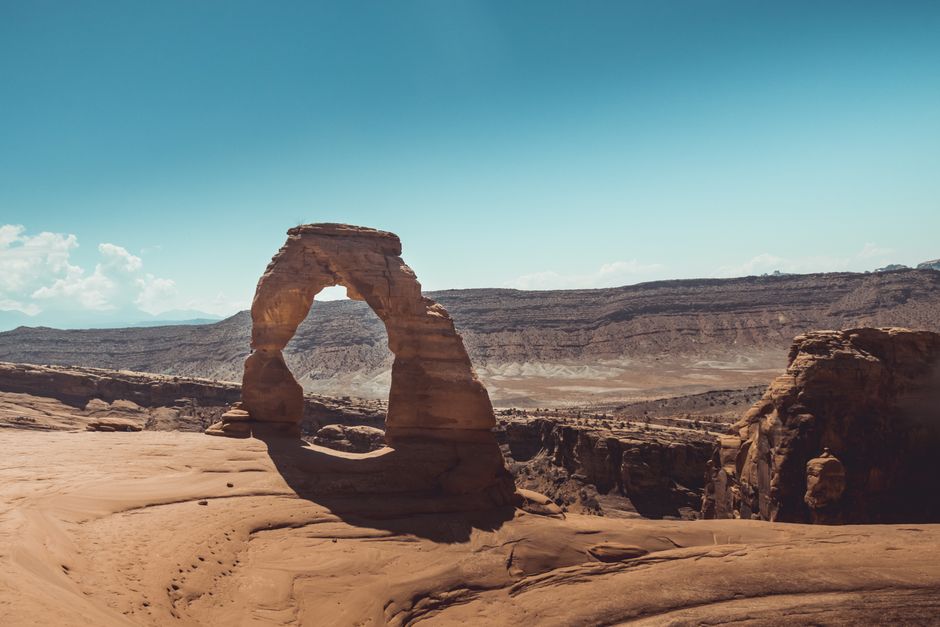 Stunning Delicate Arch surrounded by arid desert landscape under a clear blue sky in Utah.
