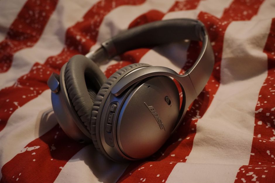 Close-up of silver wireless headphones resting on red and white patterned fabric.