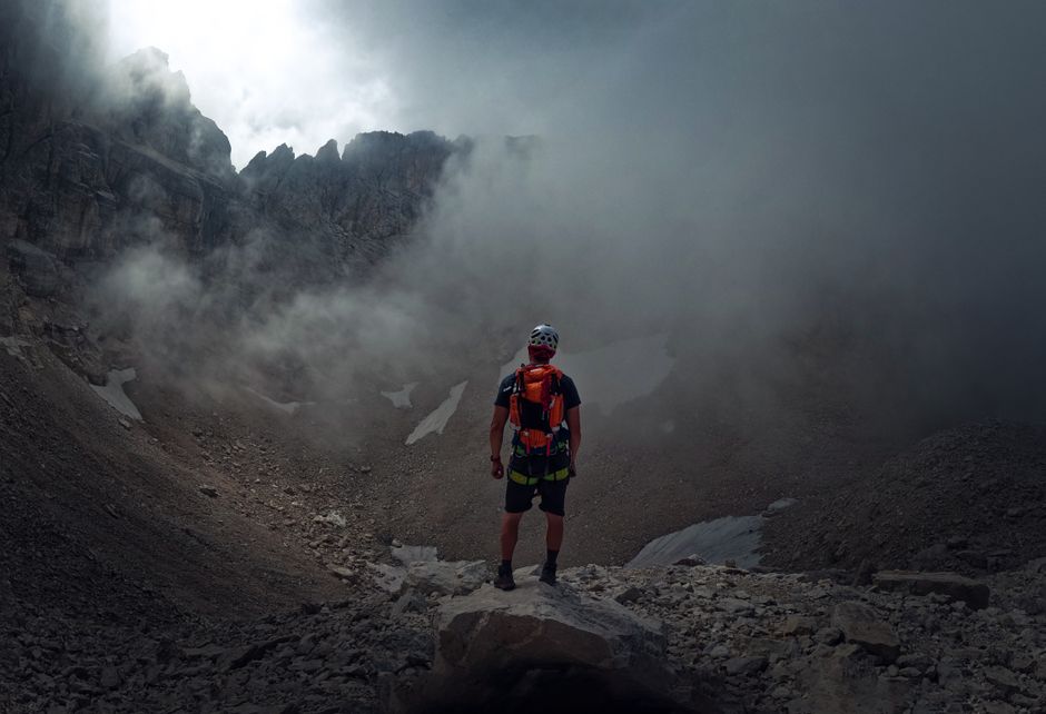 Hiker in protective gear stands amid misty mountain terrain, embodying adventure and exploration.