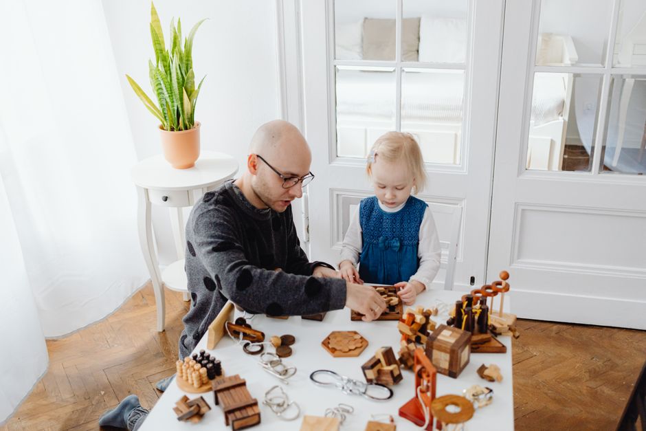 A father and daughter play with wooden puzzles in a cozy indoor setting, fostering creativity and bonding.
